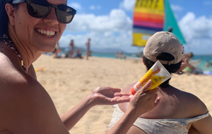 Woman applying Goodspread reef-safe mineral sunscreen to person's back outdoors